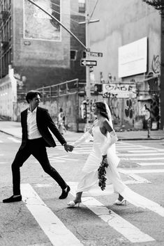 a bride and groom crossing the street holding hands