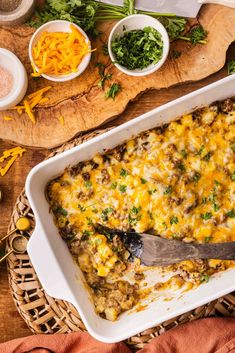 a casserole dish with cheese and vegetables on the side, ready to be eaten