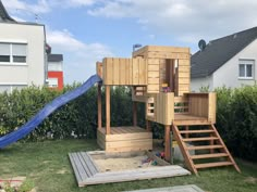 a child's wooden play set in the backyard with stairs leading up to it