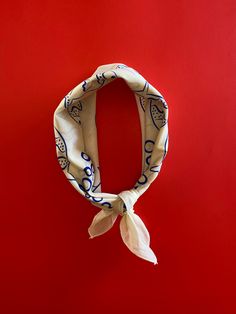 a white and blue scarf hanging on a red wall in front of a red background