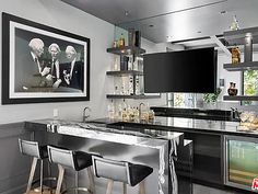 a bar with three stools and a television mounted on the wall