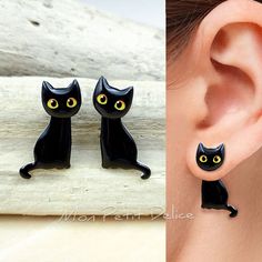 two black cats with yellow eyes are shown in front of a pair of ear studs