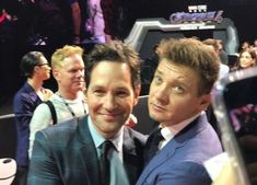 two men taking a selfie in front of an audience at a convention or show