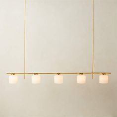 five lights hanging from a long brass bar