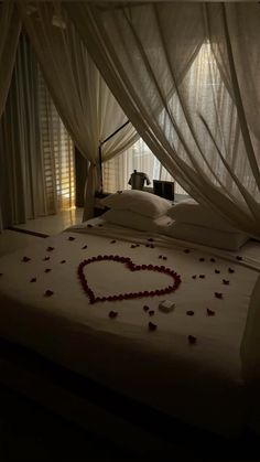 a bed with a heart made out of red hearts on top of it and white drapes