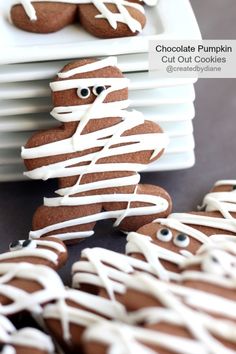 chocolate pumpkin cut out cookies with white icing on them and eyes in the middle