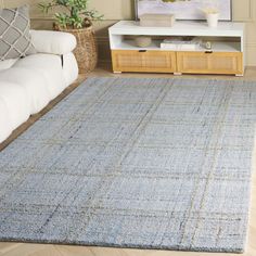 a living room with a blue rug on the floor and a white couch in front of it