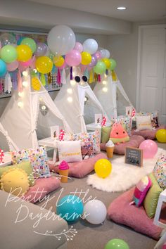 a room filled with lots of balloons and pillows on the floor next to couches