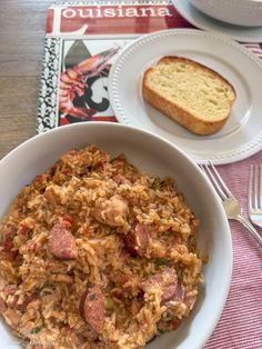 a white bowl filled with rice and sausage next to a slice of bread on a table