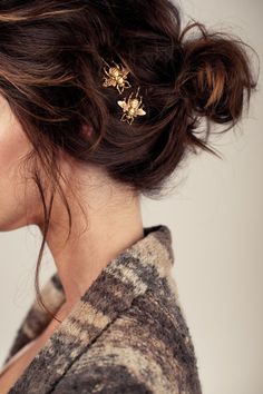 a woman with her hair in a messy bun has two small flowers on top of it