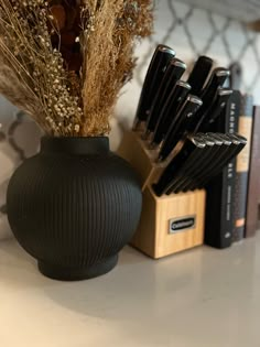 a black vase sitting on top of a table filled with knives