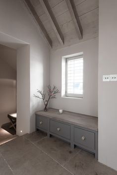 an empty room with some drawers and a vase on the counter in front of it