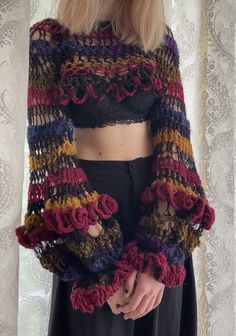 a woman wearing a crop top with crocheted ruffles on the sleeves