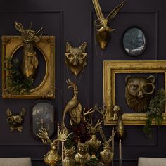 a dining room table topped with gold deer head sculptures and framed pictures on the wall