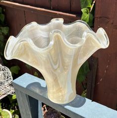 a large glass vase sitting on top of a wooden table next to a potted plant