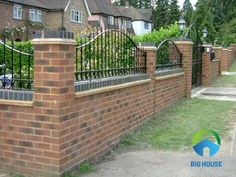 a brick fence and gate in front of some houses