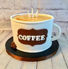 a coffee cup cake with the word coffee on it and two candles sticking out of it