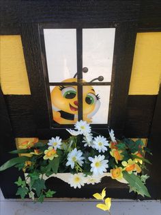 a vase with flowers in front of a door decorated to look like a smiling bee