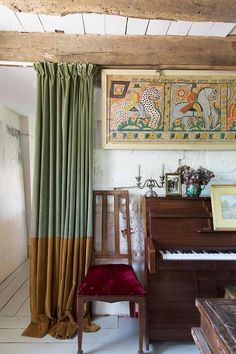 a room with a piano, chair and painting on the wall in it's corner