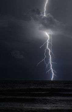 a lightning bolt is seen over the ocean