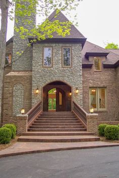 a large stone house with steps leading to the front door and entry way that leads up to it