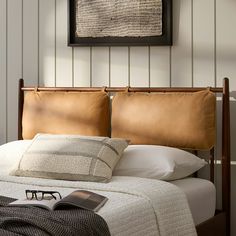 a bed with eyeglasses and a book on the pillow in front of it