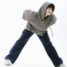 a young man in grey hoodie and blue pants posing with his arms stretched out