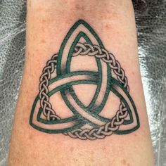 a tattoo on the arm of a person with a green and white celtic knot design