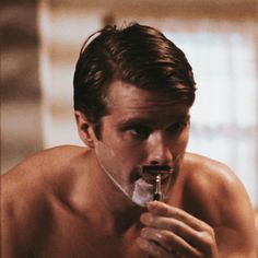 a man with no shirt is brushing his teeth