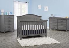 a baby's room with gray furniture and blue walls, including a crib