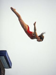 a woman diving into the water from a platform