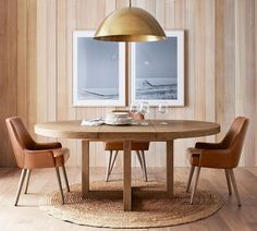 a dining room table and chairs with two pictures on the wall behind them, in front of a wooden paneled wall