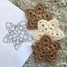 three crocheted flowers sitting on top of a piece of paper