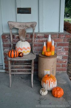 pumpkins and gourds are sitting on the porch next to an old chair