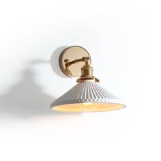 a wall light that is on the side of a white wall with a lamp attached to it