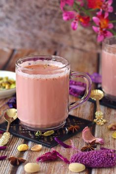 two mugs filled with pink liquid sitting on top of a wooden table