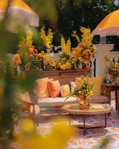 an outdoor living area with couches, tables and umbrellas