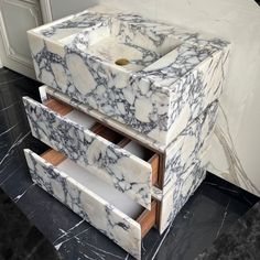 a marble sink sitting on top of a counter next to a white cabinet with drawers