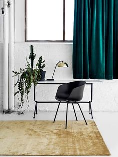 a chair and desk in front of a window with green curtains