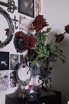 a vase filled with red flowers sitting on top of a black table next to a mirror