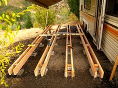 an rv is parked in the dirt next to some wooden planks