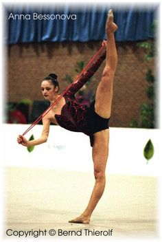 a woman doing a handstand while holding onto a pole