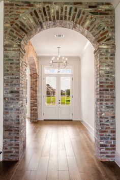 an archway leading into a house with two doors and brick pillars on either side of the door