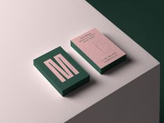 two green and pink business cards sitting on top of a white table next to each other