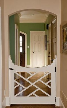 an entry way with a white gate and green walls in the background is a doorway that leads to another room