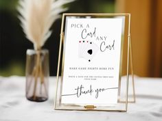 a card game is displayed on a table next to a vase with some feathers in it