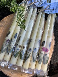 several candles are wrapped in plastic and sitting on a piece of wood next to some plants