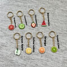 fruit keychains are arranged on a gray surface with words written in different languages