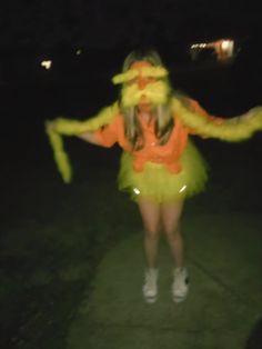 a woman in a yellow dress is dancing outside at night