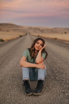 a young woman sitting on the side of a road with her hand under her head